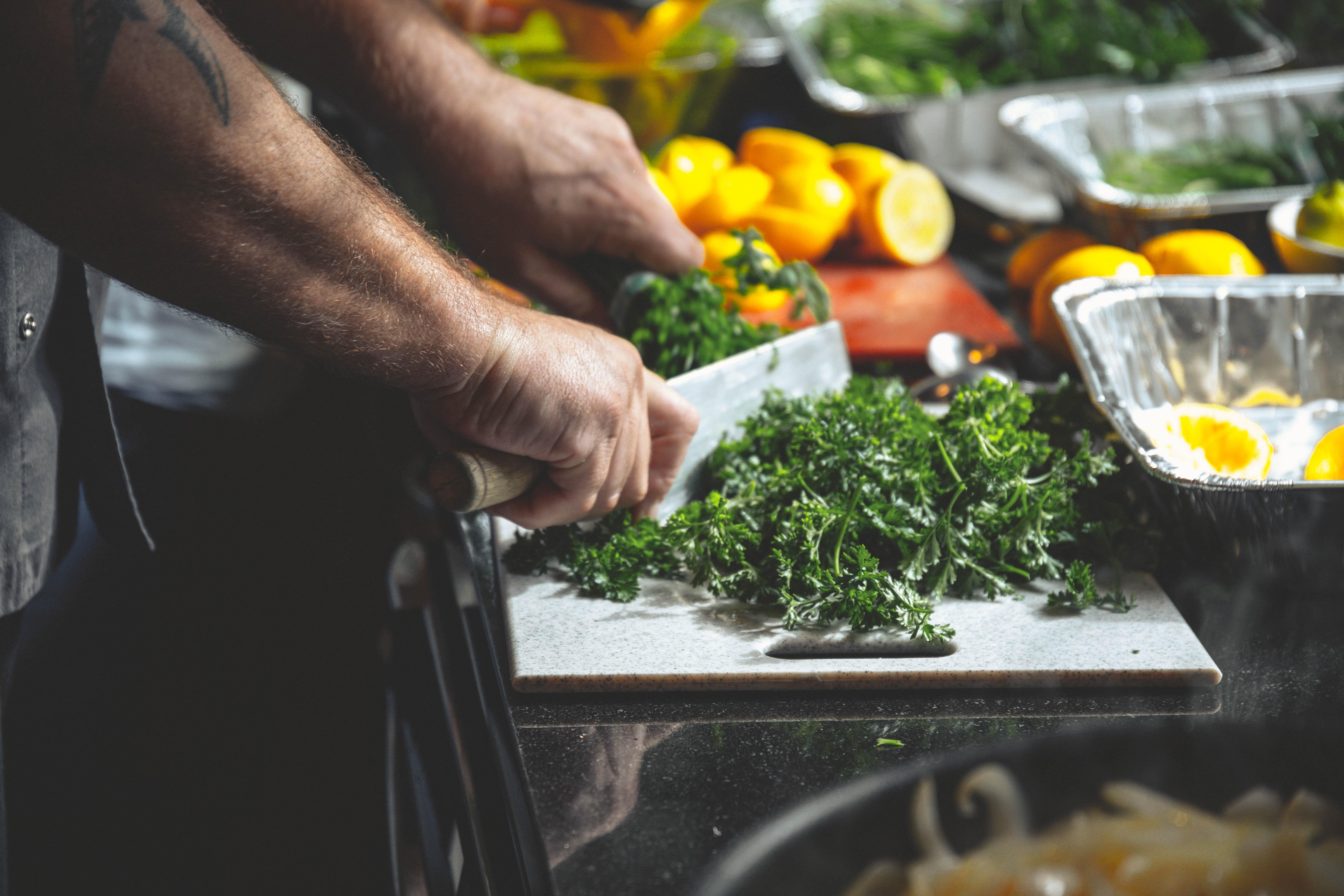 Chef in kitchen cutting vegetables - food waste 