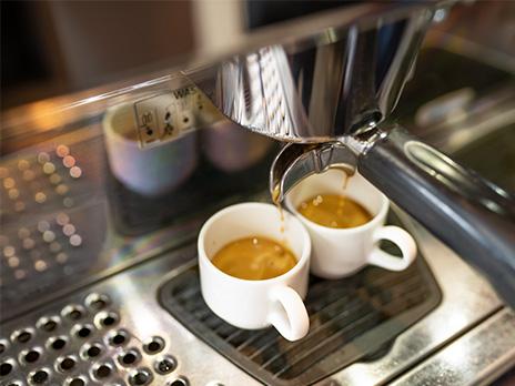 Kaffee fließt aus dem Siebträger in zwei Tassen