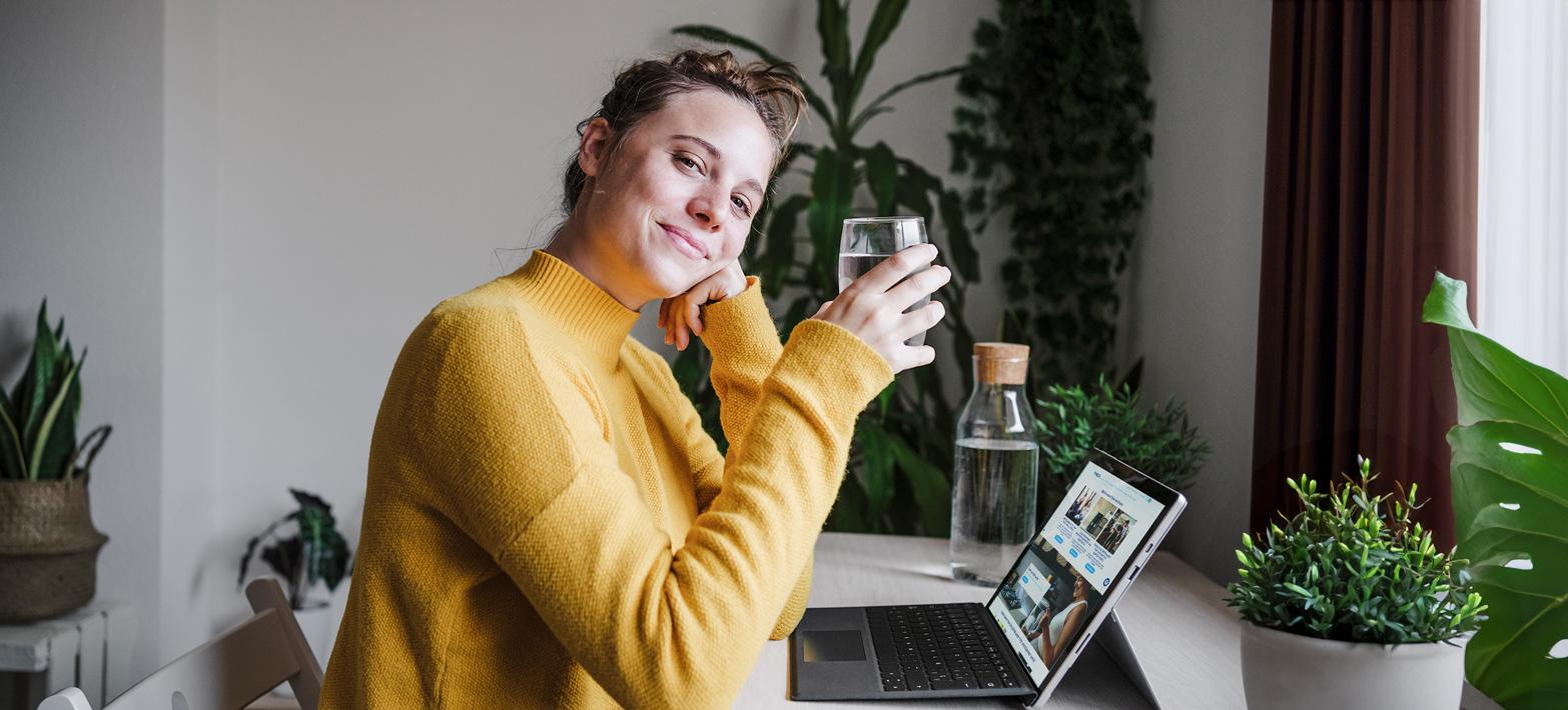 Woman sitting in front of laptop with a water glass.
