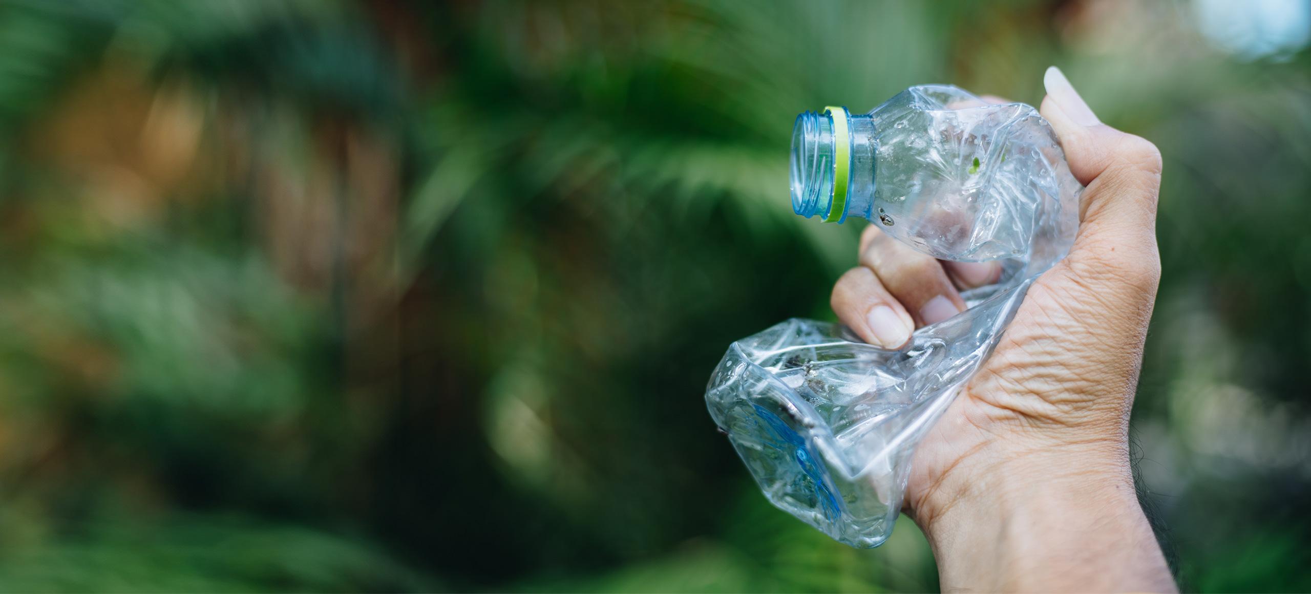 Person crushing single-use plastic bottle