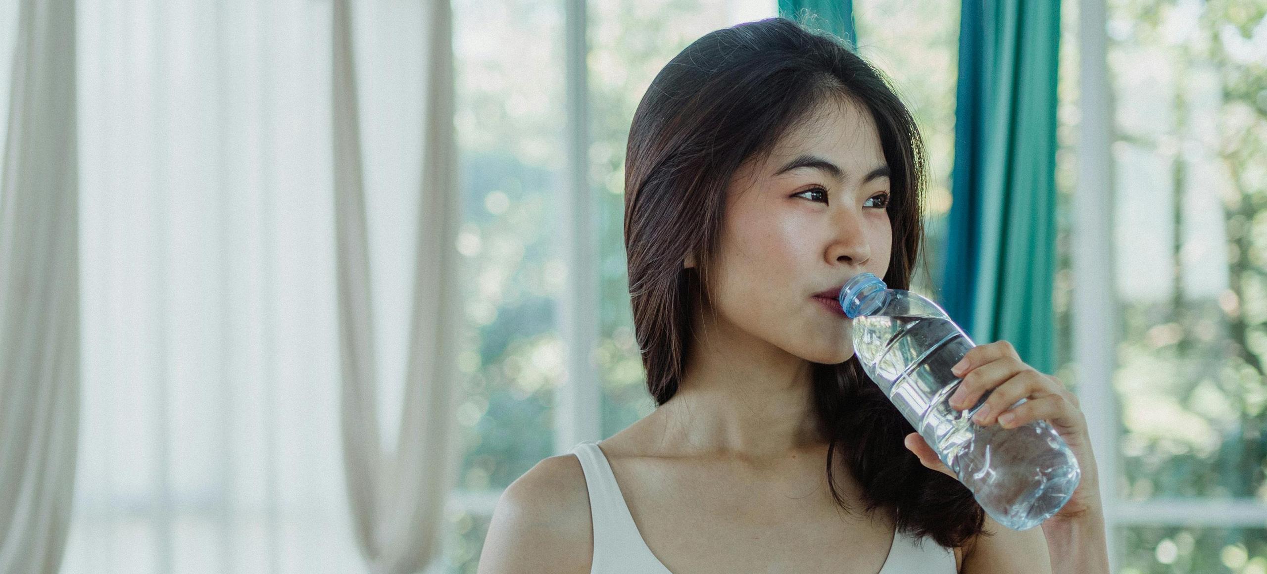 Woman drinking water from single-use plastic bottle